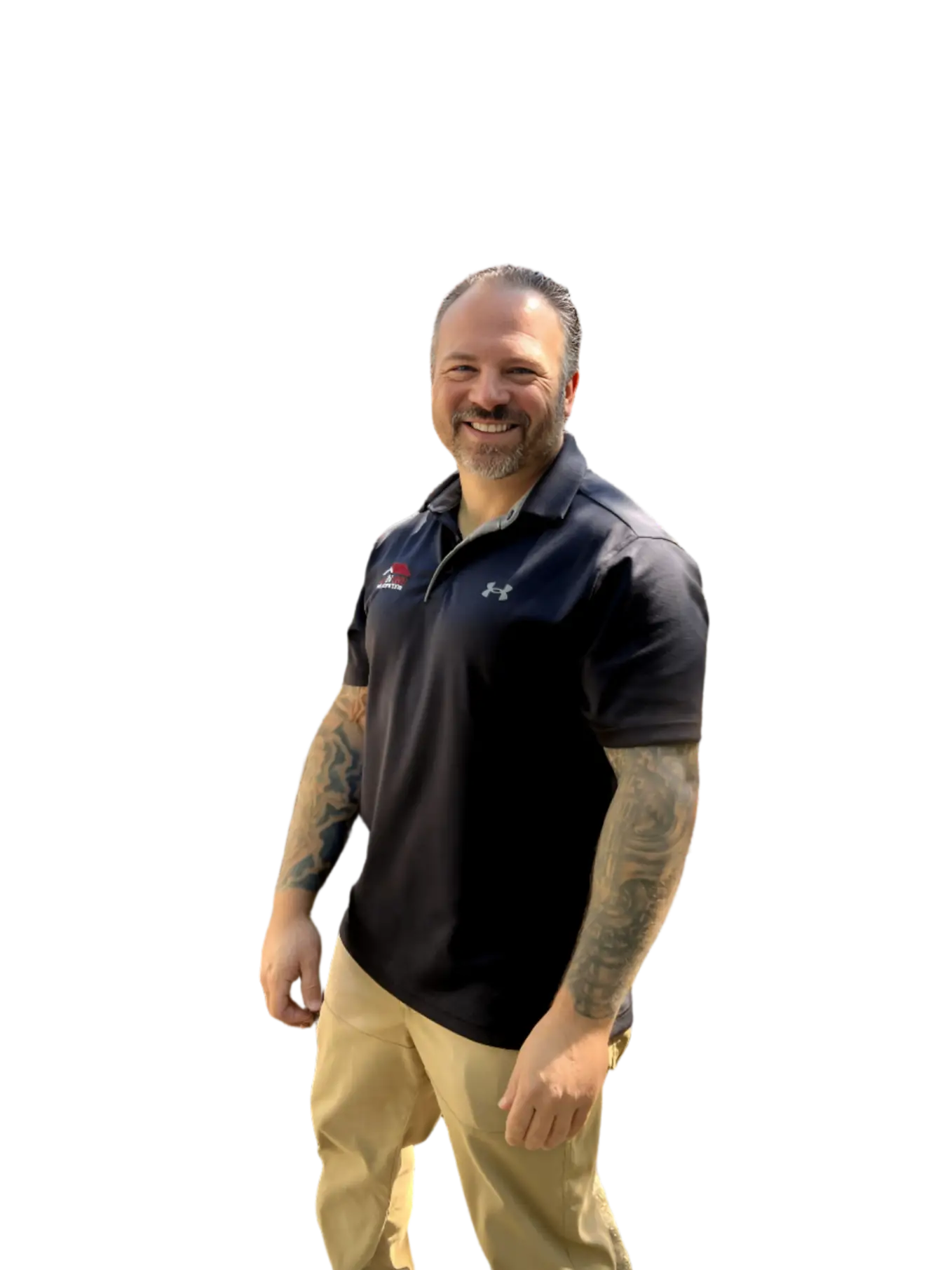A smiling man with tattoos on his arms, wearing a black polo shirt and khaki pants, stands against a plain white background.